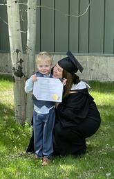 woman in a graduation cap and gown with her young son