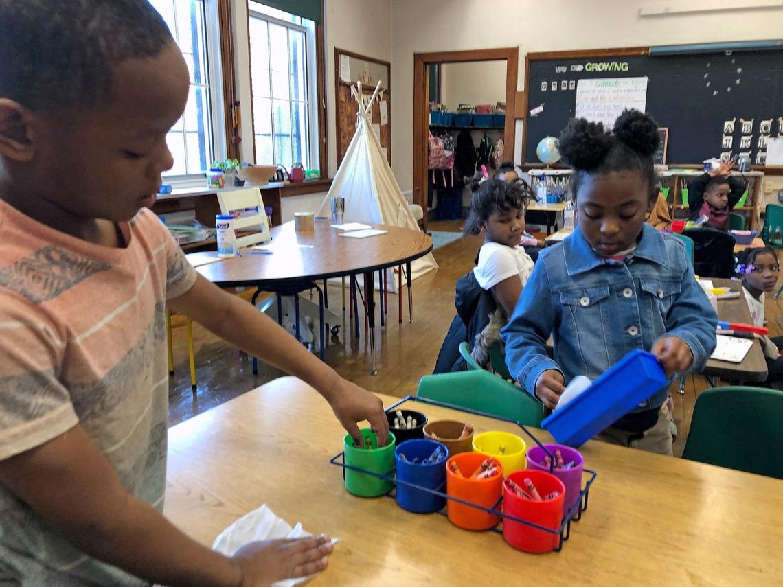 Children wipe down a table at their school