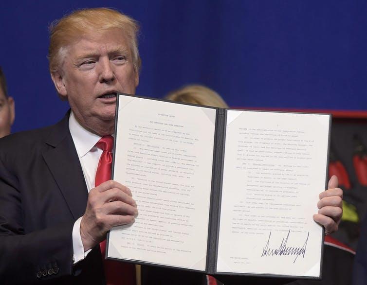 Donald Trump holds up an executive order he signed tightening the rules for technology companies seeking to bring skilled foreign workers to the U.S., on April 18, 2017