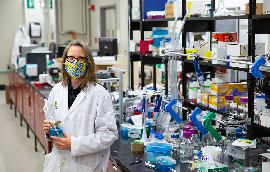Dr. Heyne holds a beaker of methylene blue solution in her laboratory