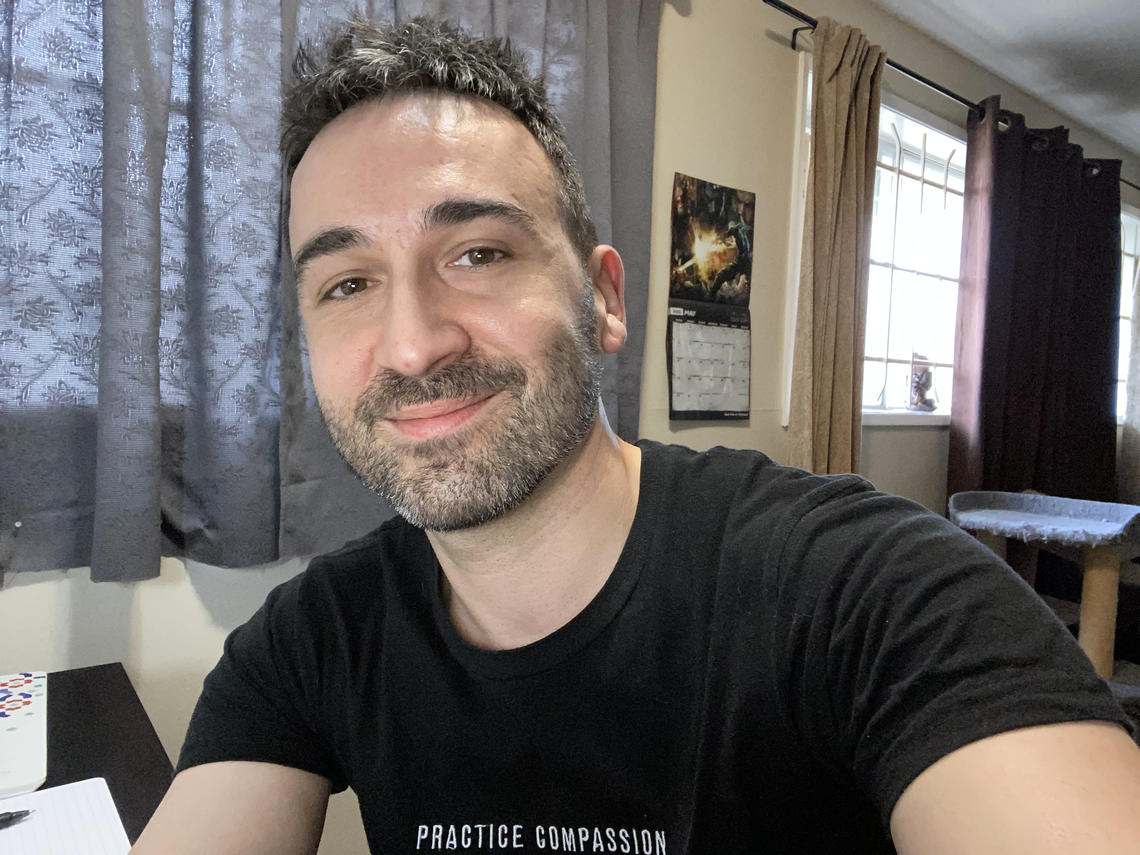 Selfie of Jake Davies wearing a black t-shirt with "practice compassion" written on it.