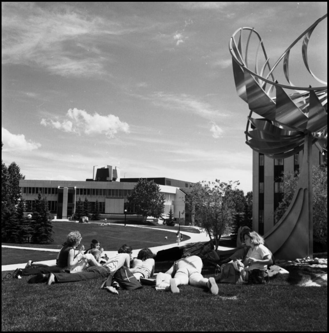  Image of University of Calgary students lying on the grass next to the George Norris sculpture (the Prairie Chicken).