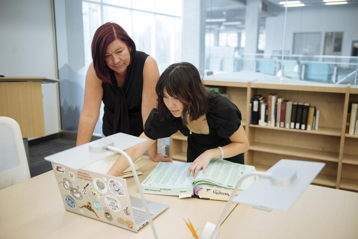 Dr. Nancy Janovicek and Katie Qin look through Calgary records at the Glenbow Western Research Centre.