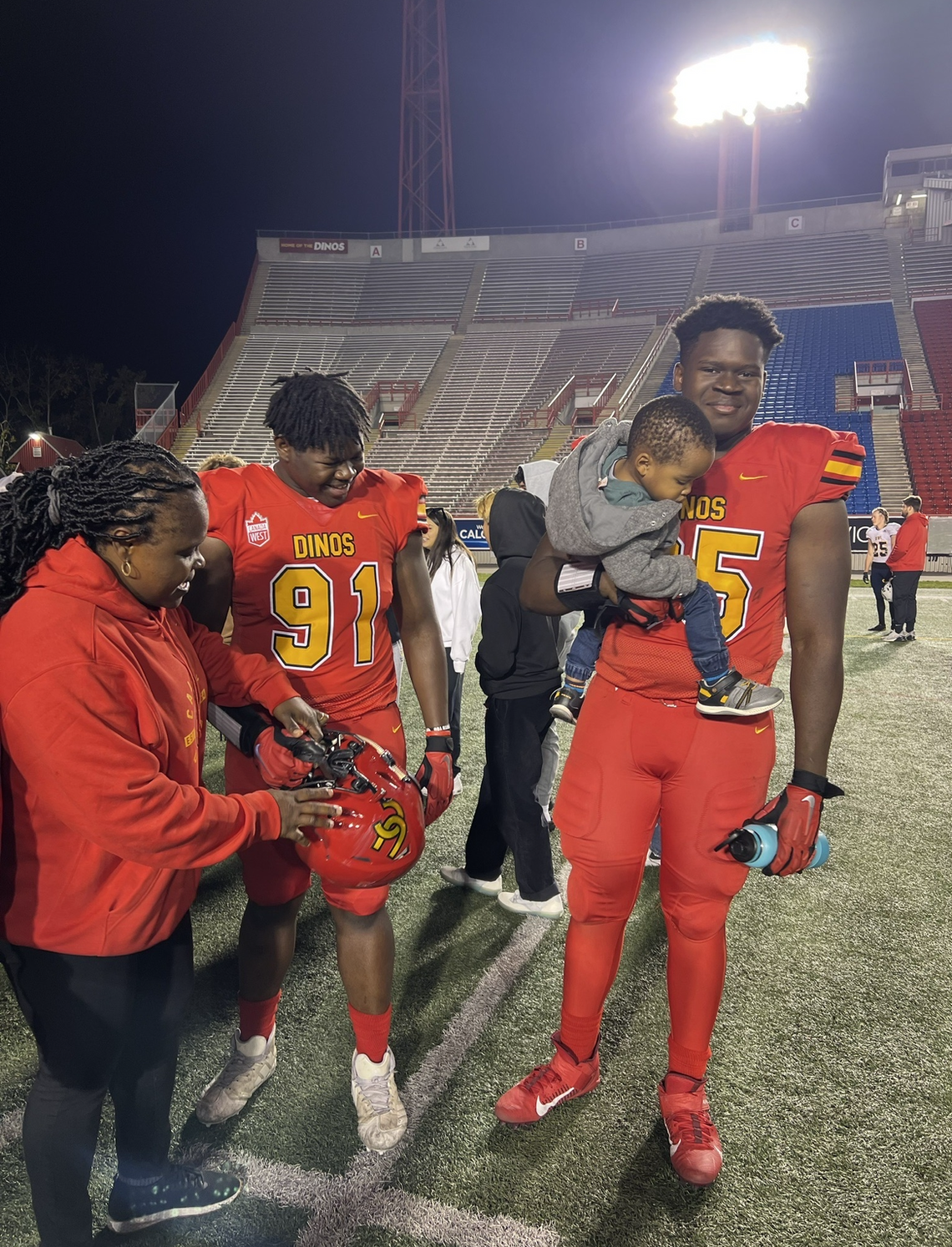 Ebele Ibelo greets her sons on the field at McMahon Stadium. 