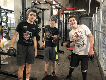 Adapted camp participants in the gym lifting weights