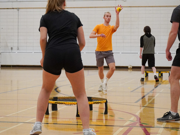 A group of students focus on a game of Spikeball. 