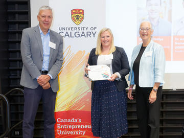 Dr. Carly McMorris (Werklund School of Education), centre, receives a Killam Emerging Research Leader Award from Killam Trustees Bill Ghali, left, and Brenda Eaton, right