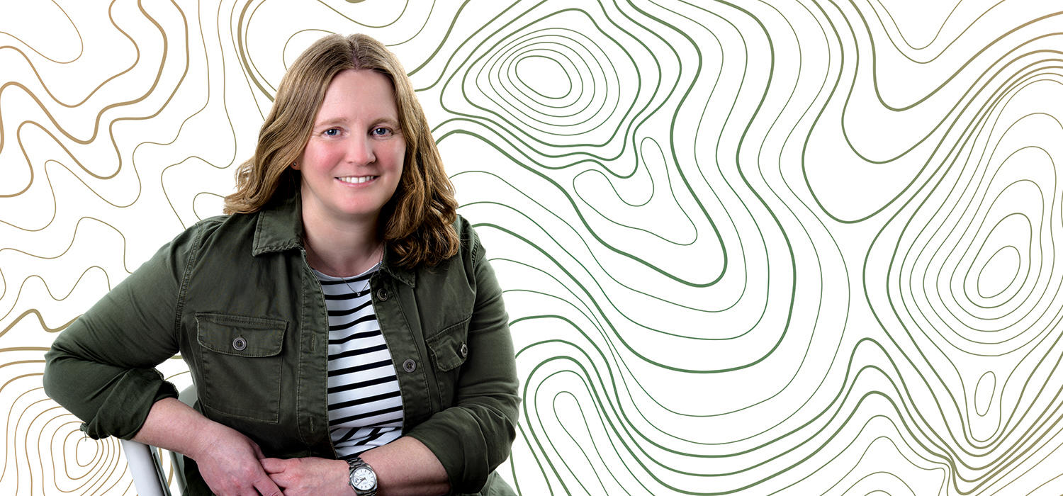 Arts researcher Petra Dolata sits on a chair. Behind her is a green graphic background that resembles tree rings.