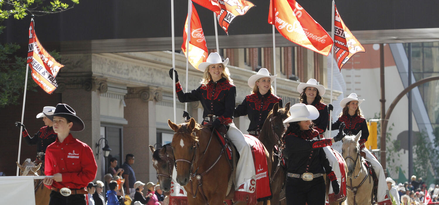 Stampede cowgirls carrying Calgary Stampede flags 