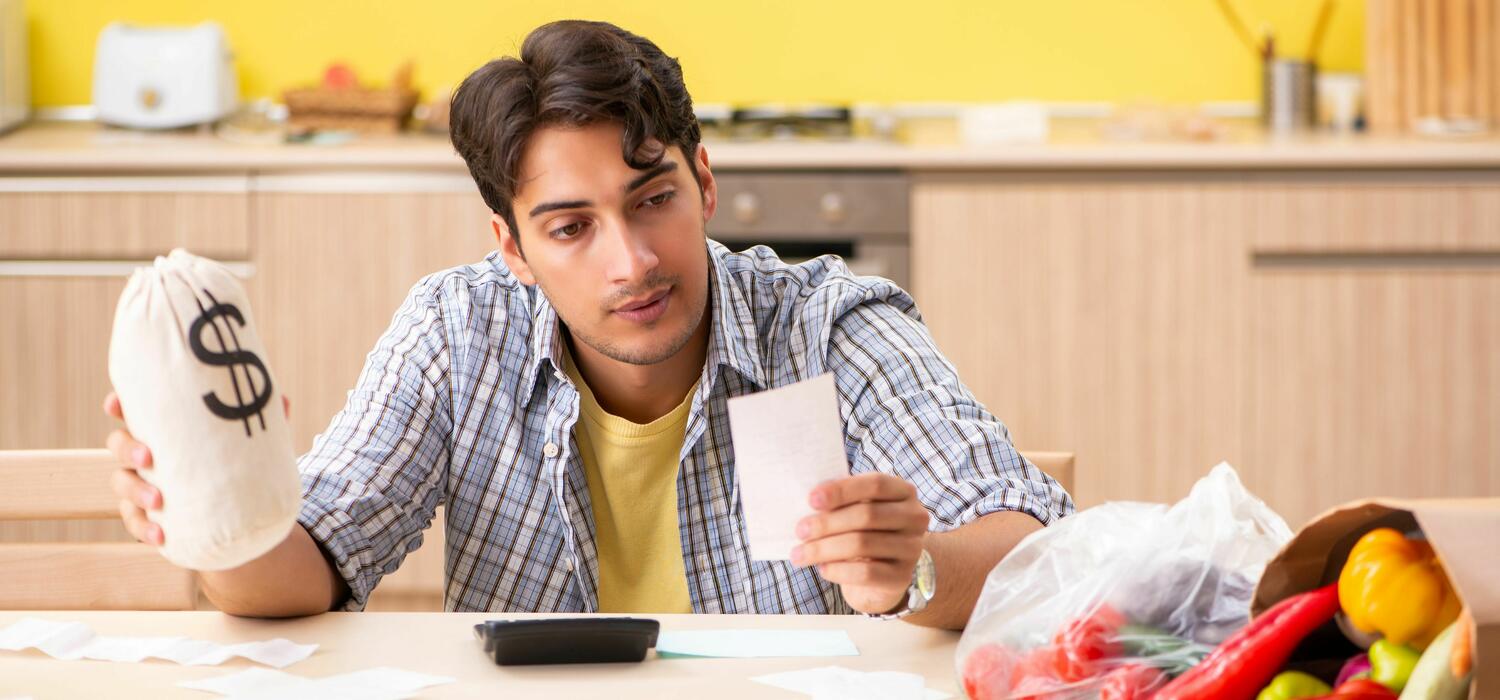 Young man checks his grocery list for affordability