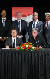 UCalgary’s Dru Marshall and Mitacs' Alejandro Adem sign a collaboration agreement that facilitates international research opportunities for students. Standing, from left: Angelo Nwigwe, Oba Harding, Ed McCauley, Andre Buret, Janaka Ruwanpura and Heather Clitheroe. Photo by Adrian Shellard, for University of Calgary International