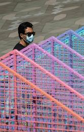 A man wearing a face mask to curb the spread of COVID-19 walks past a temporary Pride art installation in Vancouver on Aug. 3, 2020