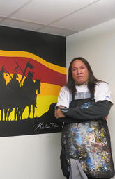 Artist Kalum Teke Dan stands beside his recently-completed mural.
