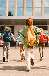 Children with backpacks walking into a building