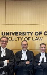 Law professors in front of Faculty of law sign.