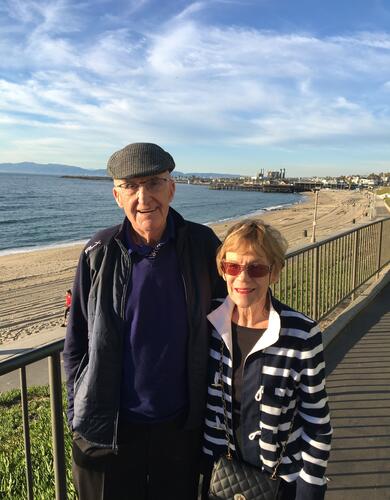 a man and woman stand on a seaside walkway